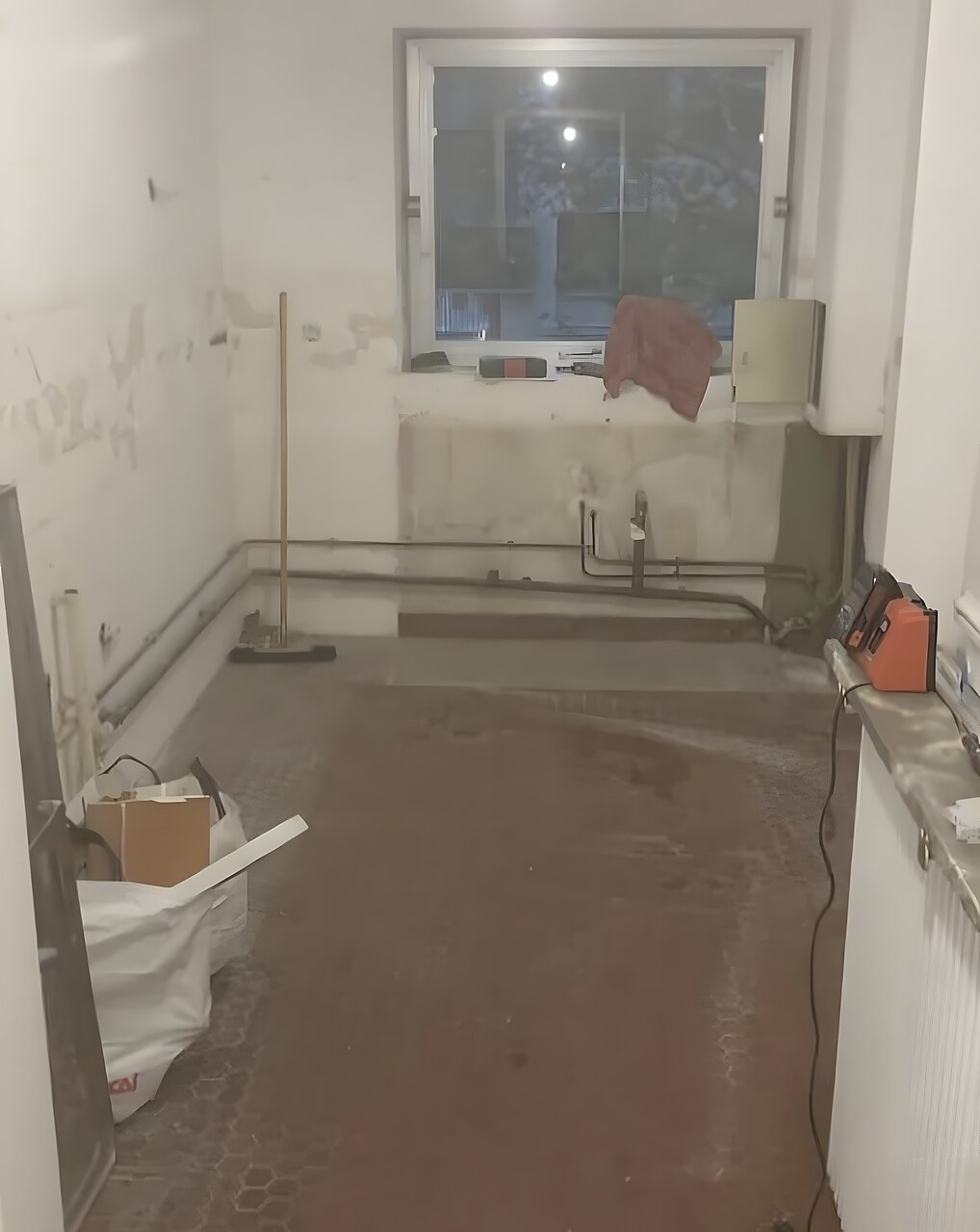 Cuisine avant rénovation : pièce vétuste, sol abîmé, murs dégradés
