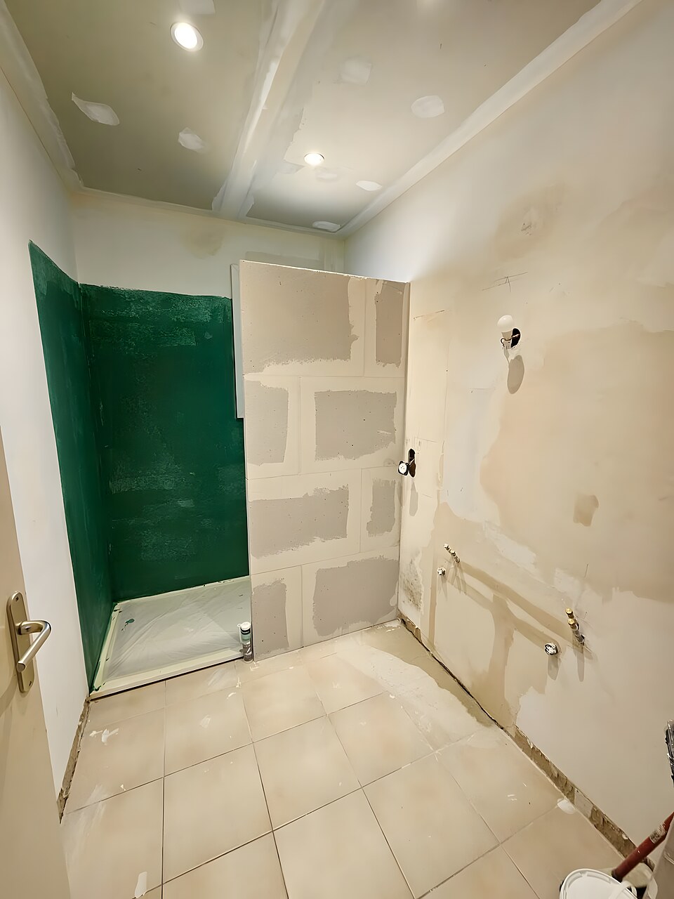 Salle de bain avant rénovation : cloisons en placo, mur en peinture verte, sol carrelé beige
